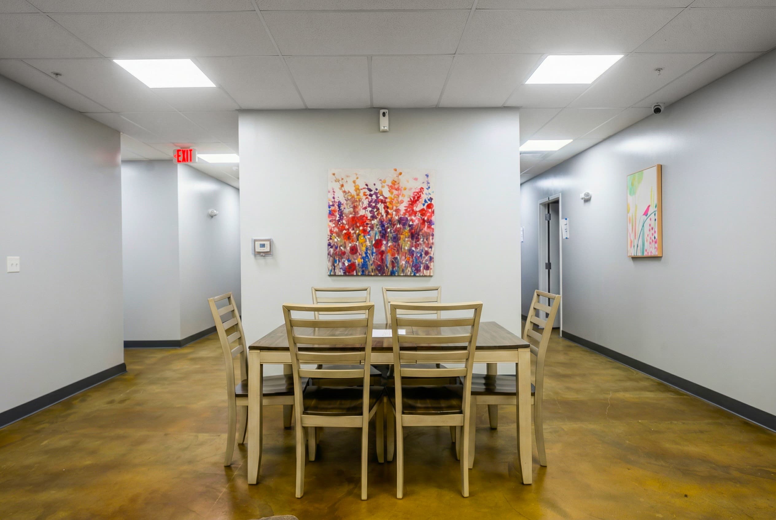 Women's dining area with a long shared table and a wildflower painting on the wall