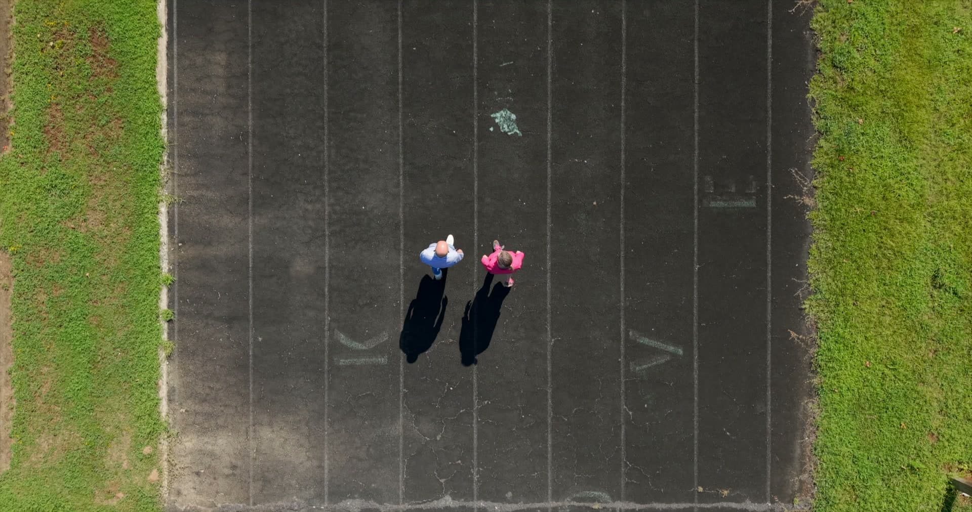 Two people walking the outdoor track together, seen from above