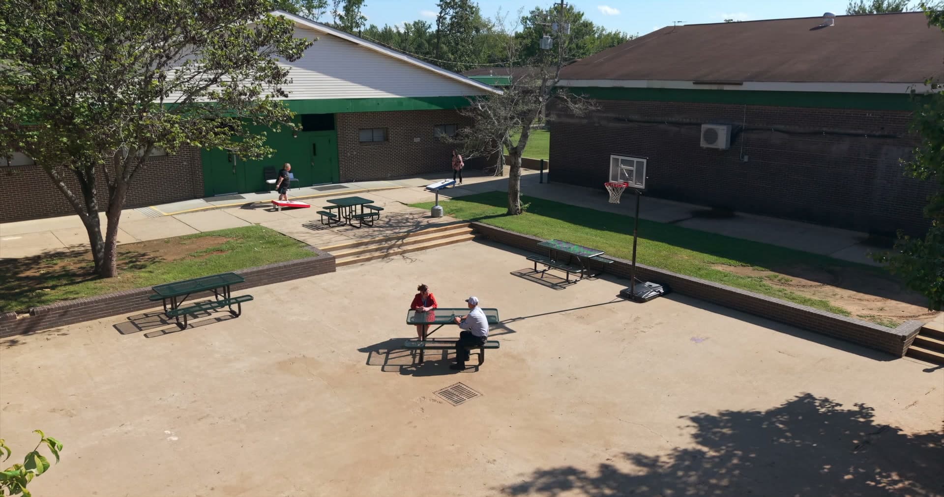 Campus courtyard from above with picnic tables, cornhole, and a basketball court