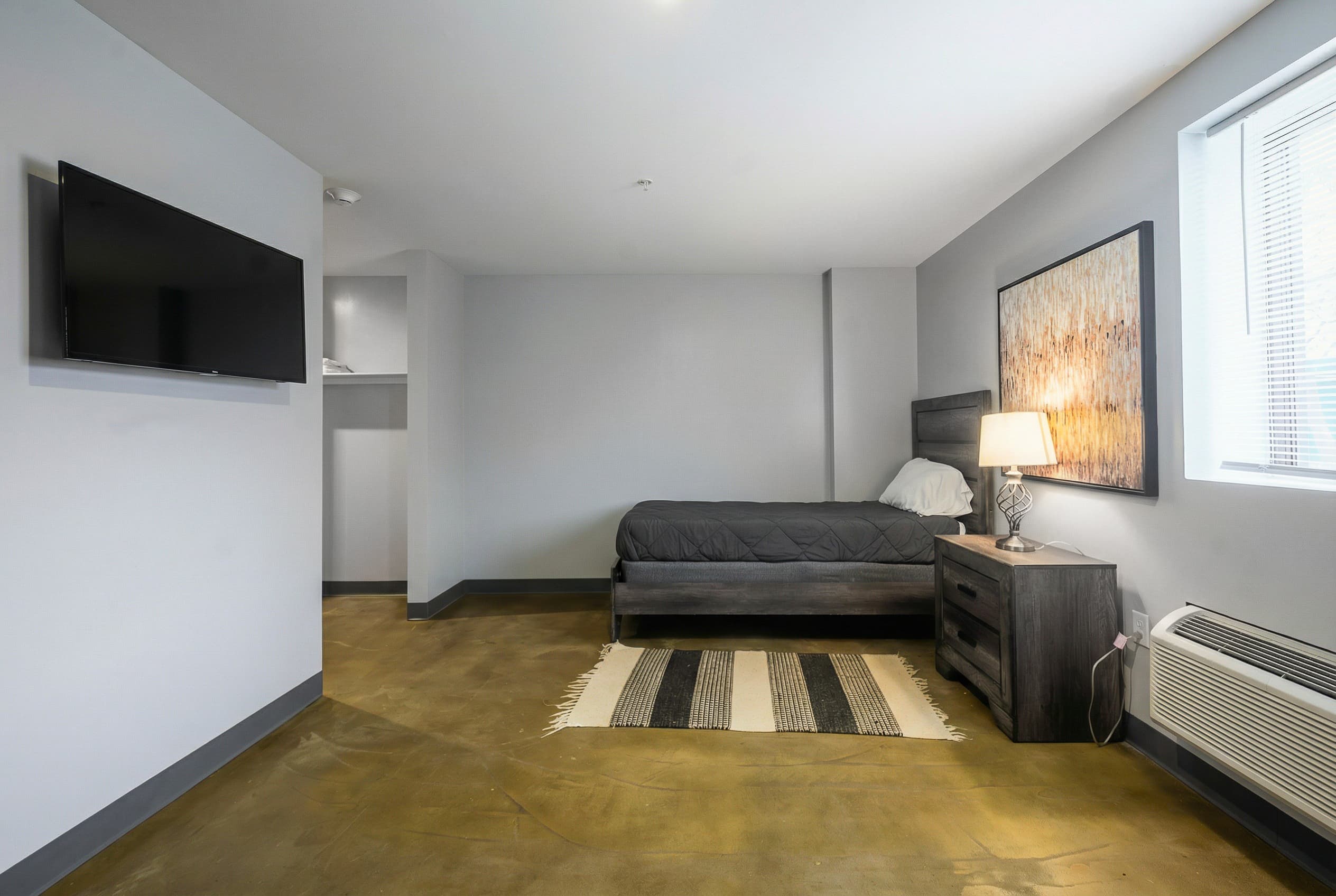 Bedroom with a mounted TV and warm wood furniture
